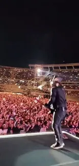 Musician performing live on stage with energetic crowd under starry night.