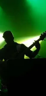 Silhouette of a guitarist on stage with green backlighting.