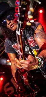 Musician plays guitar under vibrant red stage lights.