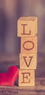 Wooden LOVE blocks with red heart on soft background.