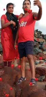 Romantic couple taking a selfie by the beach with floating red hearts.