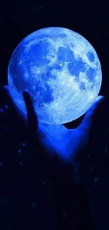 Hand holding a luminous blue moon in the dark night sky wallpaper.