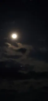 Bright moon against dark night sky with clouds.