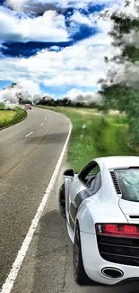 Luxury sports car on a scenic road with lush greenery and a vibrant sky.