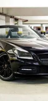 Luxury black convertible car in a parking garage.