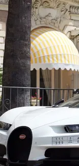 Luxury car in front of villa with yellow awning.