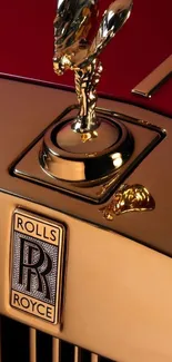 Gold Rolls-Royce emblem on a luxurious car hood.