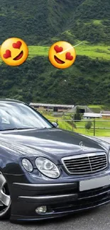 Luxury car in front of lush green mountains on a clear day.