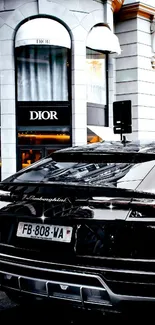 Sleek luxury car in front of Dior store, cityscape view.