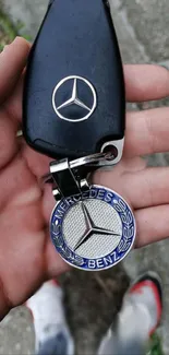 Hand holding a luxury car keychain with logo, perfect for wallpaper.