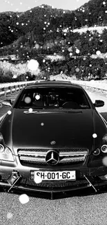 Black luxury car with mountain backdrop.