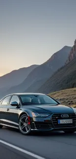 Sleek luxury car on a scenic mountain road at sunset.