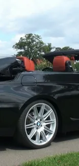 Black luxury convertible car with orange seats.