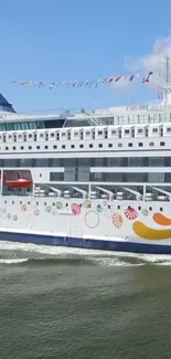 Luxury cruise ship sails under a blue sky with colorful decorations.