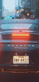 Rear view of Porsche on a rainy city street, rear lights glowing.