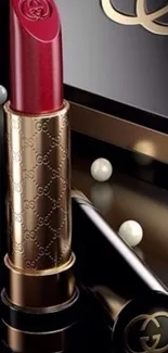 Luxurious red lipstick with gold accents on elegant wallpaper.