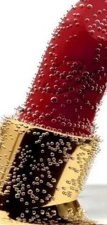 Close-up of a red lipstick with bubbles on a luxurious gold holder.