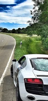 Luxury sports car on a scenic road by a lush green landscape.