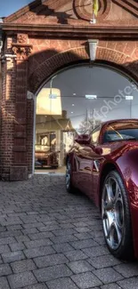 Luxury maroon sports car in front of elegant brick building.