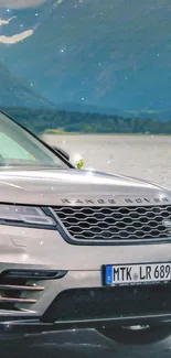 Silver luxury SUV by a mountain lake with scenic views.