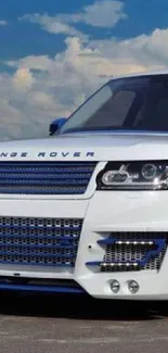 White Range Rover on open road with blue accents and cloudy sky backdrop.