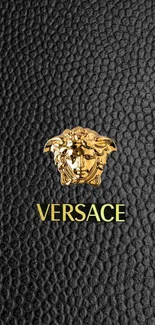 Versace mobile wallpaper with black background and golden Medusa logo.