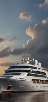 Luxury yacht sailing at sunset with calm waters and cloudy sky.