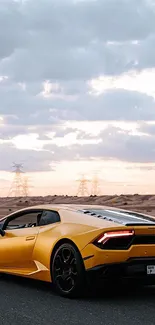 Sleek yellow sports car on a desert road under a cloudy sky.