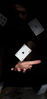 Hand surrounded by levitating playing cards in darkness.