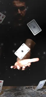 Dark wallpaper with floating playing cards and a mysterious hand gesture.