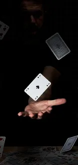 A hand surrounded by floating playing cards in a dark setting.