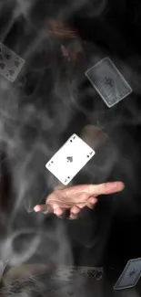 Magic hand with floating playing cards in misty dark scene.