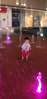 Child playing in colorful night fountain display with stars.