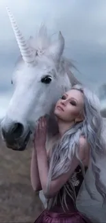 A serene woman with a unicorn in a mystical, gray-toned landscape.