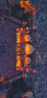 Aerial view of a lit mosque with a vibrant cityscape.