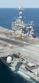 Aerial view of a large aircraft carrier cruising the ocean on a clear day.