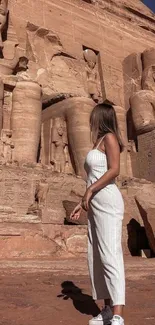 A woman stands in front of ancient Egyptian carvings under a clear blue sky.