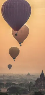 Hot air balloons over an ancient city at sunset.