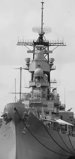 Black and white photo of a battleship docked at a harbor.