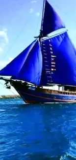 Majestic sailboat with blue sails on open ocean under clear sky.