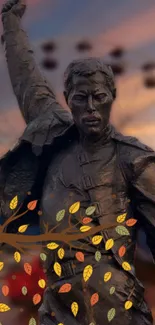 Bronze statue with autumn leaves and a sunset background.