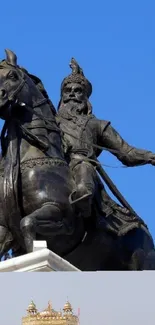 Bronze statue of a rider on a horse with a blue sky backdrop.