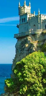 Castle on a cliff with ocean and blue sky, perfect for mobile wallpaper.