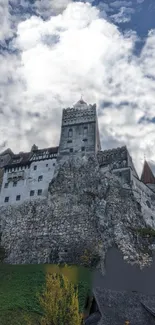 Majestic castle on rocky hill under dramatic cloudy sky.