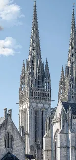 Gothic cathedral spires rise beneath a clear blue sky, showcasing architectural beauty.