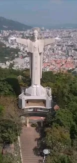 Aerial view of a grand statue overlooking a vibrant cityscape.