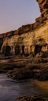 Majestic rocky cliffside during sunset reflecting in calm waters.