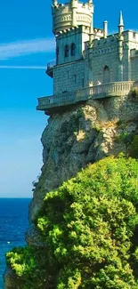 Majestic castle on ocean cliff with greenery and clear blue sky.