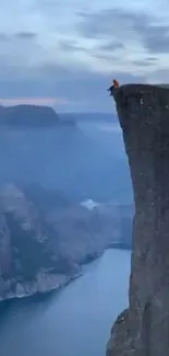 Cliffside adventurer at dusk with blue sky backdrop.