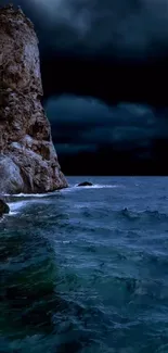 Rocky coast under a dark night sky with ocean waves.